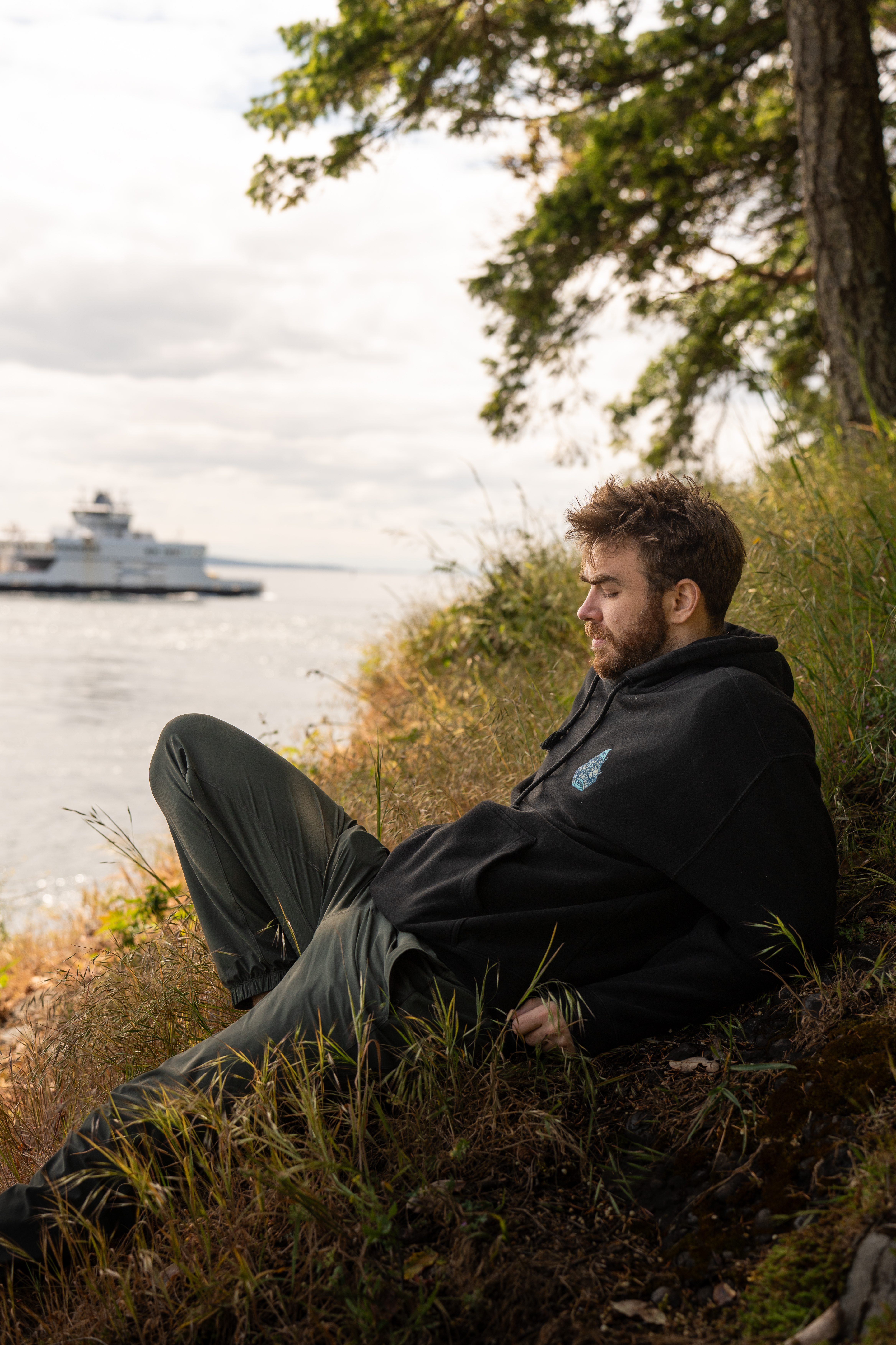 Man sitting by river bank looking beyond